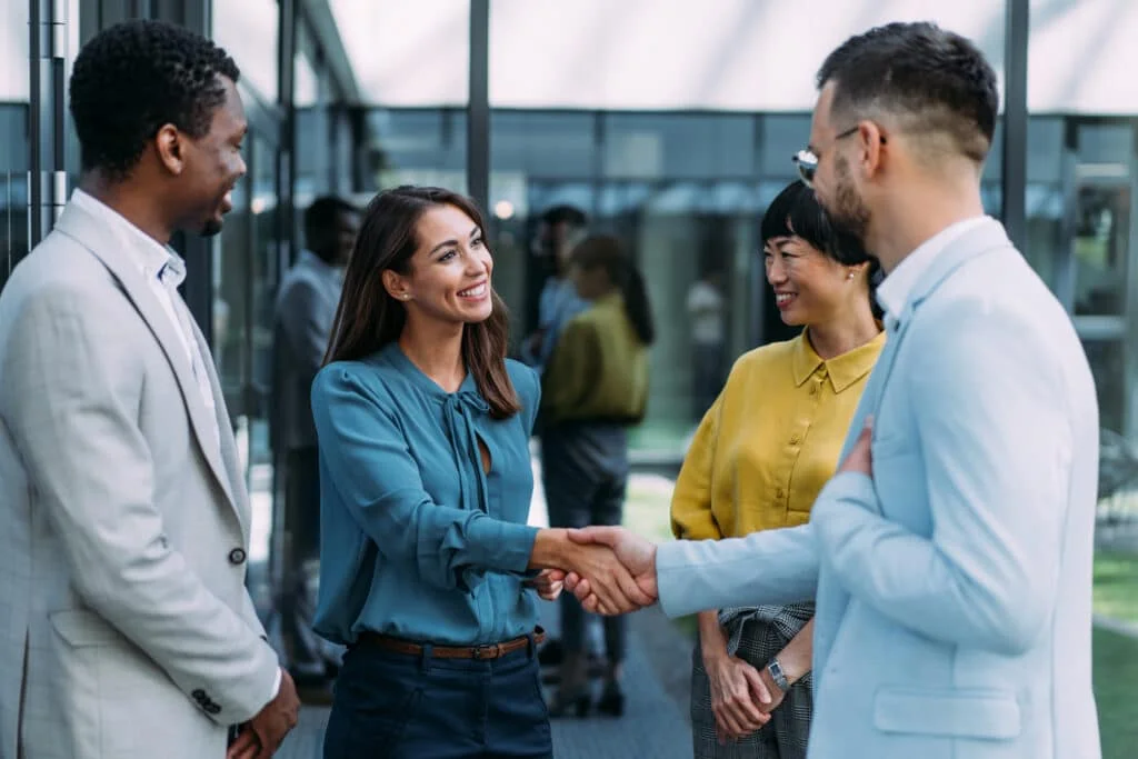 A new female employee is greeted by her teammates and shakes hands